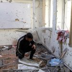 An Afghan journalist inspects a damaged classroom  after yesterday’s attack at the university of Kabul