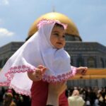 A Palestinian woman liftung a girl on the first Friday of the holy fasting month of Ramadan in Jerusalem’s Old City