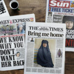 Aerial view of a woman reading a newspaper and computer laptop on wooden table
